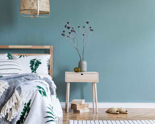 Minimalistic-composition-of-bedroom-interior-with-wooden-bed,-shelf,-flowers-in-vase,-rattan-lamp,-books-and-elegant-accessories